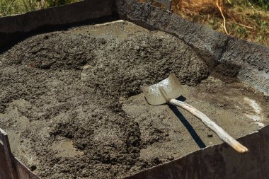 Mixing fresh cement mortar in a metal bath. mixing with a shovel fresh concrete mortar for building a house. sand with cement and water