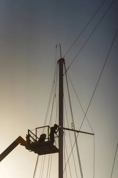 welding works of the mast on the ship. repair of sail holders on a yacht using a hydraulic platform. work of a welder at height