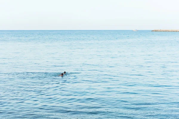 two guys race across the sea. boys cross the sea channel at speed in cyprus. young guys swim in the sea without lifeguards