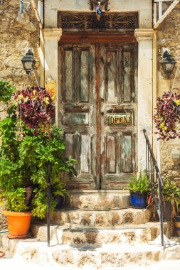 old door near the house close to the sea. wooden door with peeling paint in the seaport. atmospheric door for tourists in cyprus