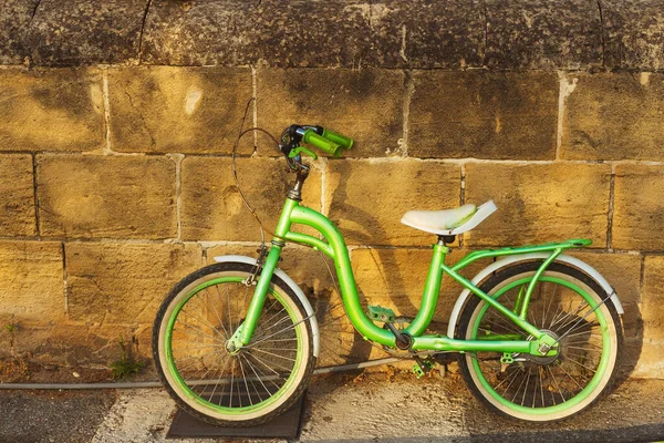 children\'s green bike near the stone wall. parking for city bikes in cyprus