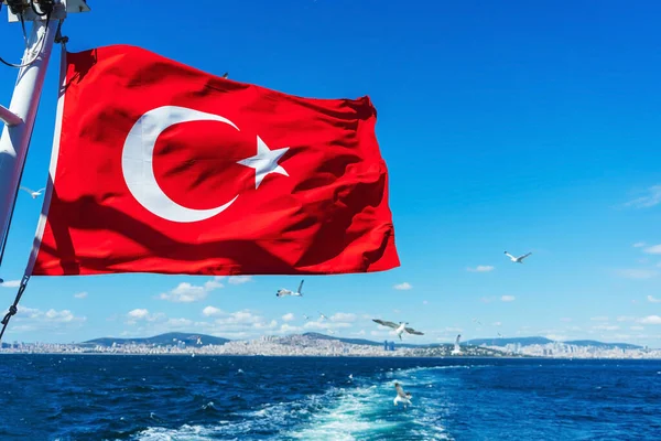 red state flag of turkey against the background of the blue sea. a flag with a star and a crescent on a passenger ship.