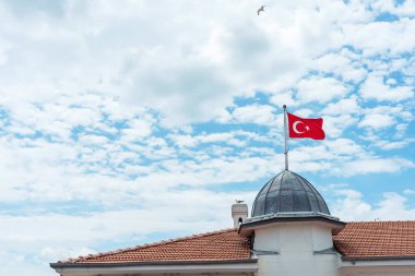 Binada kırmızı hindi bayrağı var. Evin kubbesinde yıldız ve hilal olan bayrak.