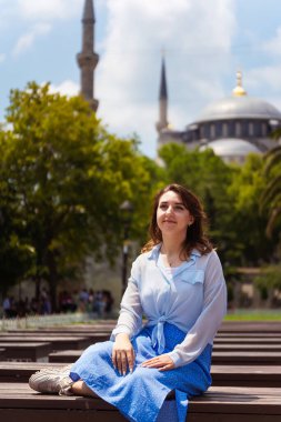 Caminin arka planında mavi etekli Avrupalı bir kız. İstanbul 'da Sultan Ahmet' in arka planına karşı bir kızın fotoğraf çekimi. İstanbul 'da bir turistin fotoğrafı ilgi odağı oldu