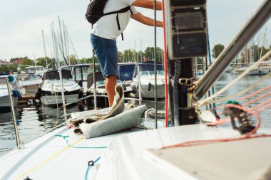 Yelkenli bir yatta erkekler için başlangıç kursları. Bir adam sürat teknesinde yelkenliden ip çeker. İpi bir vinçle sağlama alıyorum.