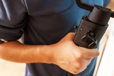 Bir adam kameraya elektronik dengeleyici tutuyor. Koçanla sağ elinle çalış..