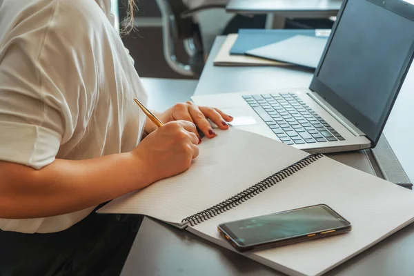 woman writes on a blank sheet of paper. recording client data in a real estate office in Turkey. office work girls at the table