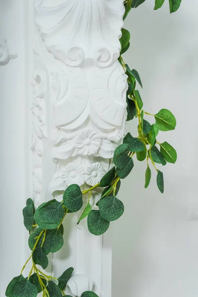 plaster element on a decorative fireplace in a photo studio. white detail of a fake fireplace with artificial flowers. plastic flowers on a plaster element