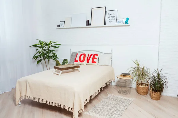 an iron bed with a light knitted plaid against a brick wall. a double bed in a bright room in a photo studio. a photo zone for a family photo shoot