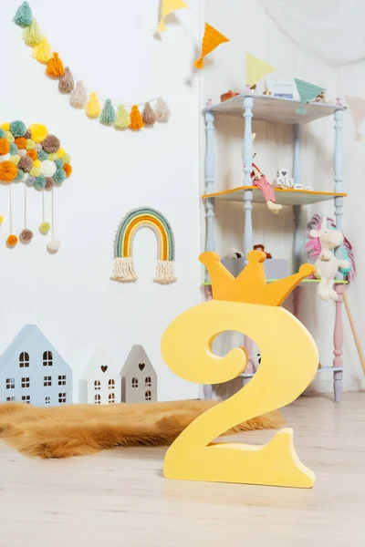 number two in the children's room. number two from polystyrene against the background of toys and a wooden house in the room of a small child. light photo zone with a number in a photo studio