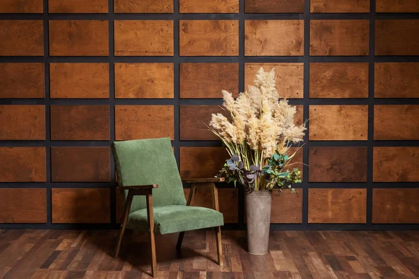 wooden armchair on the background of a wall with wooden inserts. classic photo zone with a chair for a wedding photo shoot. brown room with green armchair