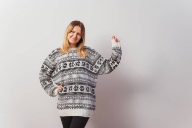 Beyaz bir duvarda örülmüş kazaklı Rus kız. Türk yılbaşı süveteri giyen Slav kız ışık duvarına ördü. Fotoğraf çekimi için üzerinde yıldızlar olan bir Noel süveteri.