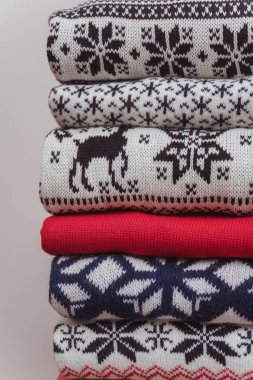 Yeni yılın sıcak örülmüş süveterleri üst üste yığıldı. Örülmüş Noel kazakları beyaz bir arka planda katlanır. Örülmüş Noel kazaklarının dokusu.
