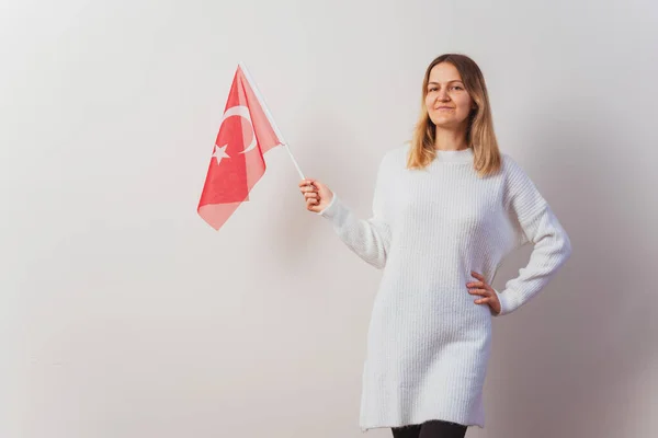 Russian girl in a knitted dress with a Turkish flag in her hands. Russian girl migrated to Turkey. Christmas knitted pullover on a Slavic woman. immigration girls in istanbul