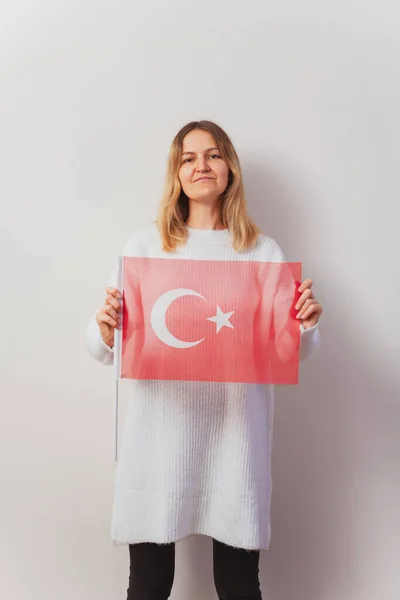 Russian girl in a knitted dress with a Turkish flag in her hands. Russian girl migrated to Turkey. Christmas knitted pullover on a Slavic woman. immigration girls in istanbul