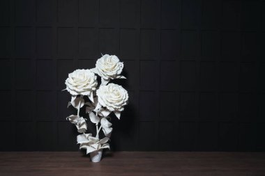 Siyah arka planda beyaz, dev, yapay güller. Bir fotoğraf stüdyosundaki siyah bir duvarın arka planındaki plastik büyük çiçekler. Gotik stil düğün fotoğrafı bölgesi