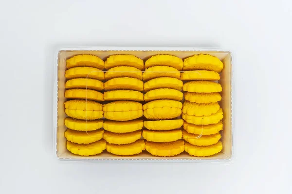 yellow round cookies in a box on a light background. Crumbly cheap cookies in a container on a white background. photo of confectionery for the catalog