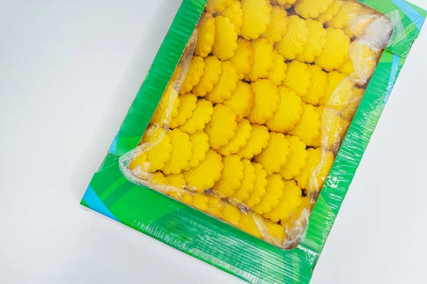 yellow round cookies in a box on a light background. Crumbly cheap cookies in a container on a white background. photo of confectionery for the catalog