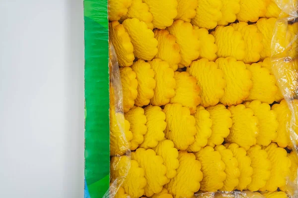 yellow round cookies in a box on a light background. Crumbly cheap cookies in a container on a white background. photo of confectionery for the catalog