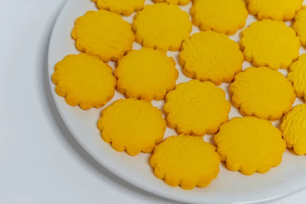 yellow round cookies on a light background. Crumbly cheap cookies on a plate on a white background. photo of confectionery for the catalog