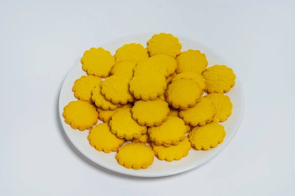 yellow round cookies on a light background. Crumbly cheap cookies on a plate on a white background. photo of confectionery for the catalog