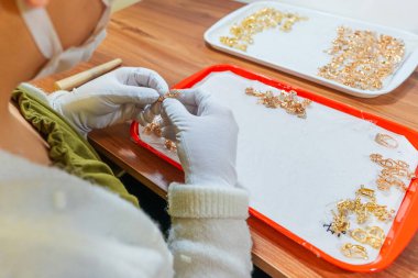 İşletmedeki altın ürünlerinin kalite kontrolü. Markete gönderilmek üzere altın yüzük ve küpe hazırlanıyor. Fabrikada değerli taşları olan altın mücevher üretimi.