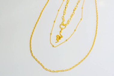Beyaz arka planda altın bir çağrı. Hafif arka planda altın kaplama bijouterie zinciri. Katalog için bojouterie fotoğrafları