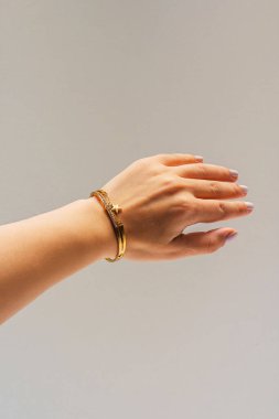 Beyaz arka planda altın bileziği olan bir kadın eli. Üzerinde yaldızlı mücevherler olan bir kız. Katalog için bojouterie fotoğrafları