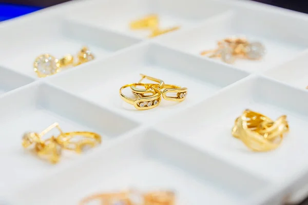 金の宝石でトレイを表示します 金の指輪とイヤリングを持った小さな細胞が人に売るために 宝石用の区画付きの白いプラスチック製の箱 カタログの金の宝石の写真 — ストック写真