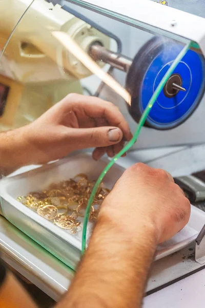 polishing gold jewelry on special equipment. work of a jeweler with gold rings. production of gold dyes at the factory. jewelry polishing at the enterprise