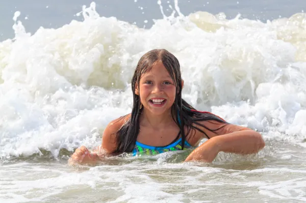 Giovane ragazza che gioca in onde oceaniche . Immagine Stock