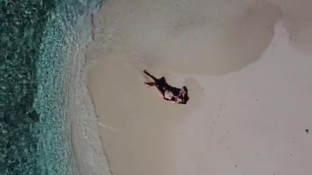 Veduta aerea di una spiaggia circondata da onde con una donna che prende il sole sdraiata su una sabbia — Video Stock