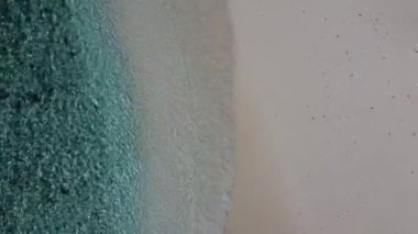 Okyanus dalgalarının havadan görünüşü boş beyaz bir kumsalda yuvarlanıyor, Maldivler.