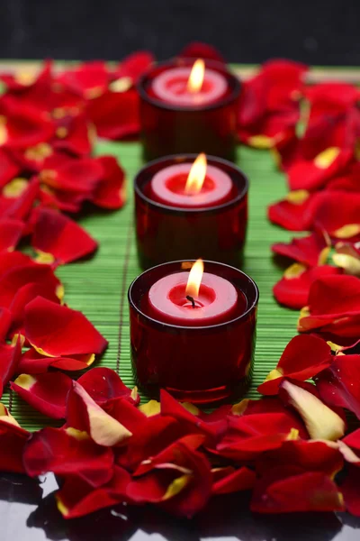 Candele con petali di rosa rossa Foto Stock