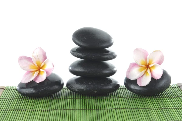 Frangipani flower and stacked stones on mat — Stock Photo, Image