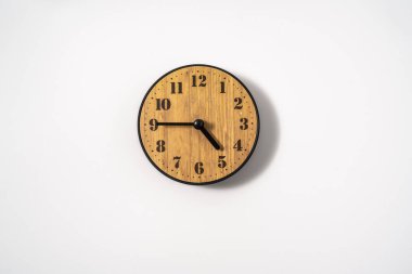 Beyaz zemin üzerinde beyaz kadranlı ahşap ofis duvar saati. Beyaz arkaplanda duvar saati, en üst görünüm.