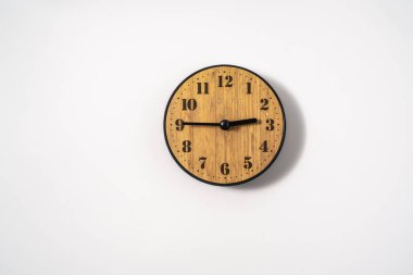 Beyaz zemin üzerinde beyaz kadranlı ahşap ofis duvar saati. Beyaz arkaplanda duvar saati, en üst görünüm.