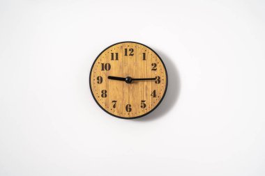 Beyaz zemin üzerinde beyaz kadranlı ahşap ofis duvar saati. Beyaz arkaplanda duvar saati, en üst görünüm.