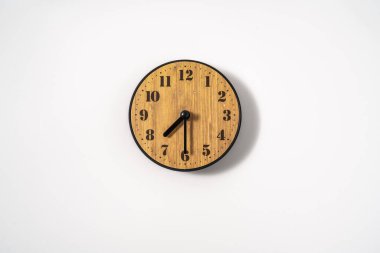 Beyaz zemin üzerinde beyaz kadranlı ahşap ofis duvar saati. Beyaz arkaplanda duvar saati, en üst görünüm.