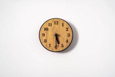 Beyaz zemin üzerinde beyaz kadranlı ahşap ofis duvar saati. Beyaz arkaplanda duvar saati, en üst görünüm.