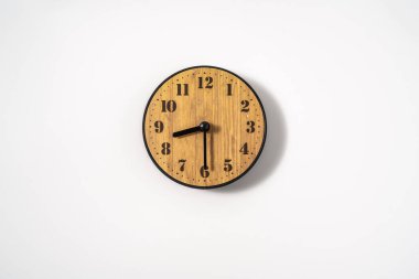 Beyaz zemin üzerinde beyaz kadranlı ahşap ofis duvar saati. Beyaz arkaplanda duvar saati, en üst görünüm.