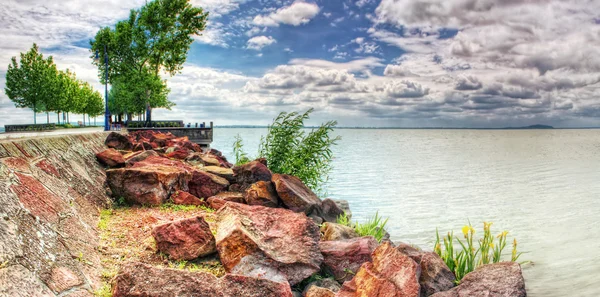 Pier with trees, flowers and huge stones. — Stock Photo, Image