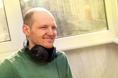 Kulaklıklı yakışıklı genç adam. Bir adamın gülümsemesi. Büyük kulaklıklı adam. Sakallı ve endişeli yüzlü bir adam müzik dinler. Müzik ve rahatlama kavramı. Mutlu adam.