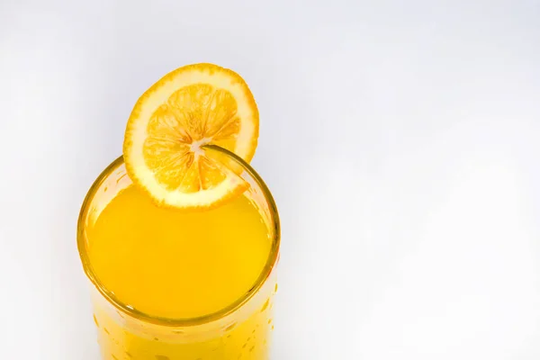 Lemon juice and a slice of lemon. Lemonade close-up on a white background. Cold summer drink in a glass with lemon juice. A piece of lemon in a glass