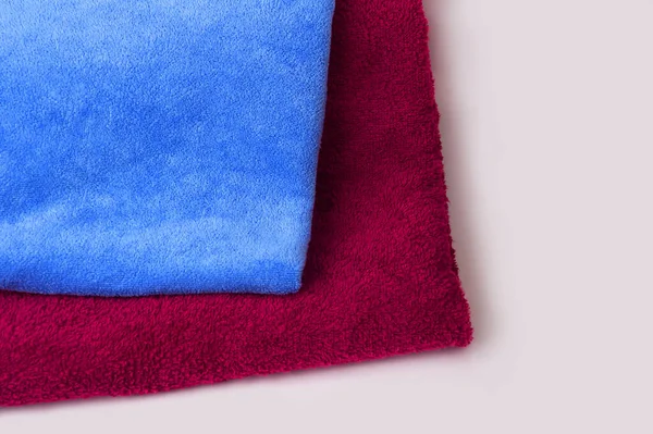 Blue and red towel on a white background. Folded fresh towels close up. Terry-colored fabric