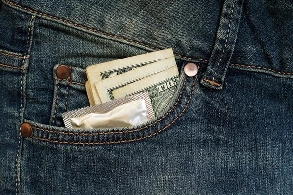 Preservativo e três dólares no bolso jeans — Fotografia de Stock