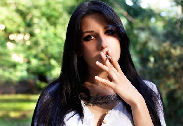 Young girl with tattoo smokes — Stock Photo, Image