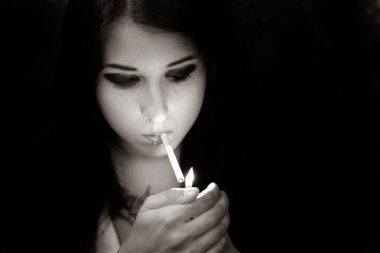 Kız içinde siyah ve beyaz bir sigara yakıyor