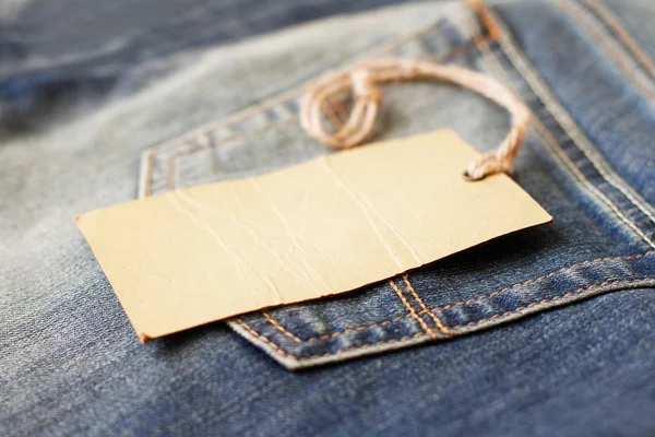 Blank paper label with string on jeans — Stock Photo, Image