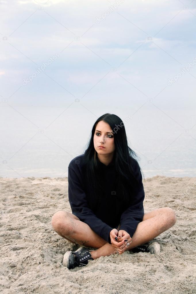 Sad teenager girl sitting on the beach
